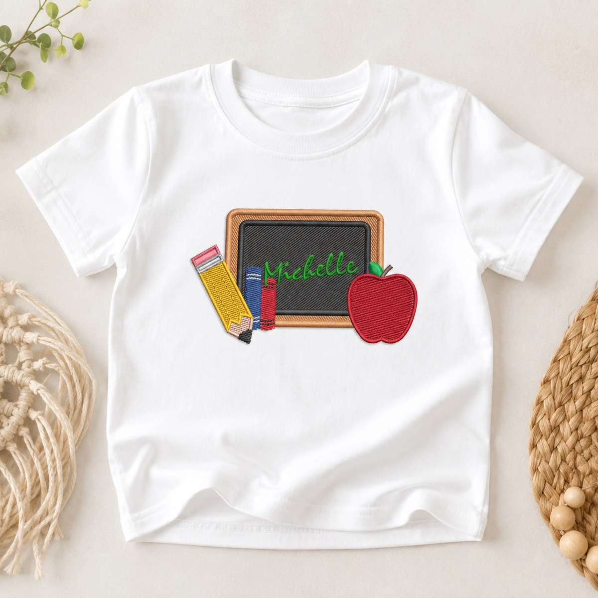 Back to school supplies embroidery design with chalkboard, pencil, books and apple stitched on a white kids T-shirt