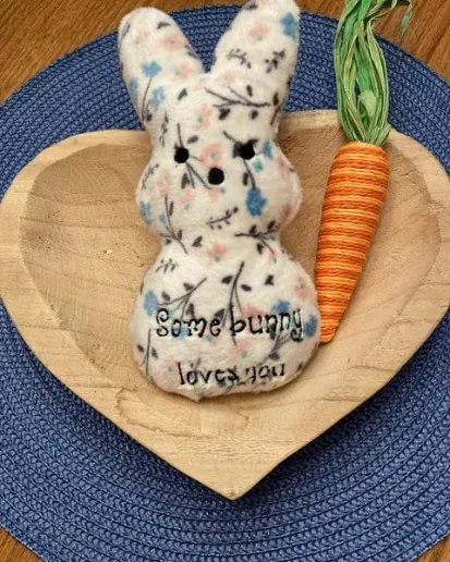 In-the-hoop bunny stuffie embroidered with Some bunny loves you next to a toy carrot