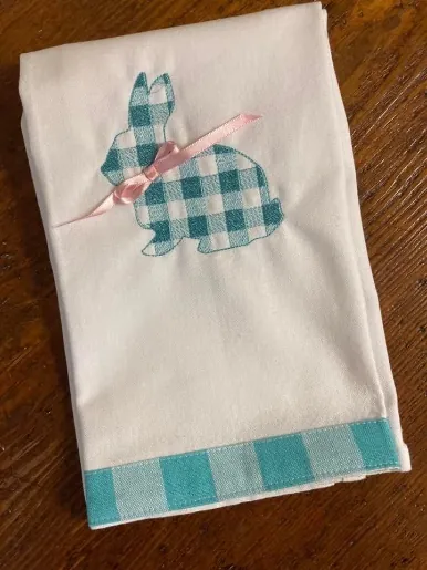 Buffalo plaid bunny silhouette embroidery on a white kitchen towel with a pink ribbon bow