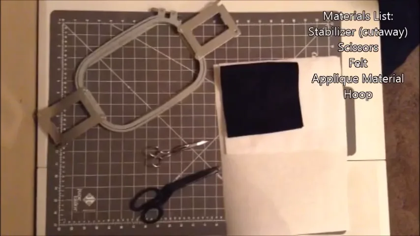 Materials for a machine embroidered patch: hoop, cutaway stabilizer, black felt, applique fabric and scissors