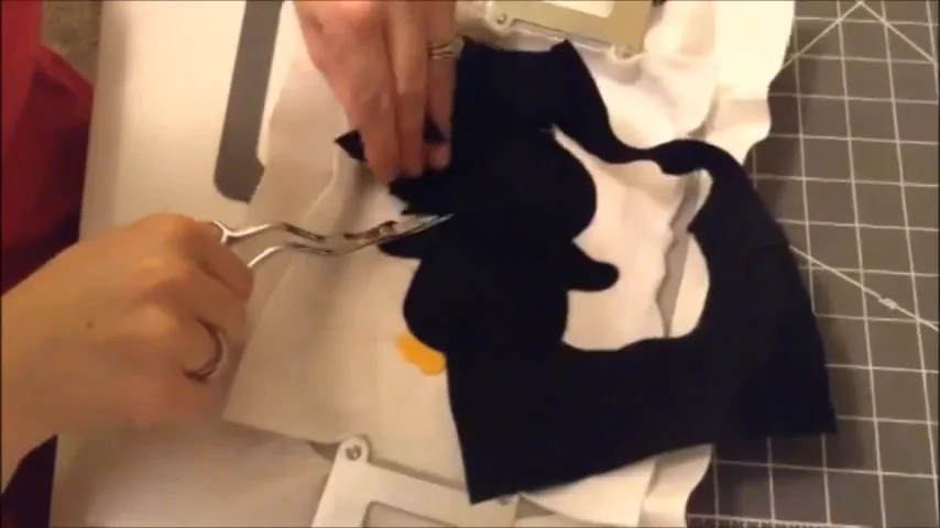 Trimming excess felt close to the tack-down stitches with applique scissors
