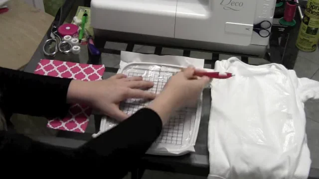 Marking the center of hooped stabilizer with the hoop template before floating a onesie