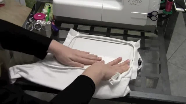 Smoothing the front of the onesie onto sticky stabilizer so it lies flat without stretching