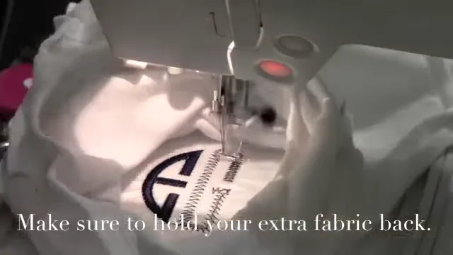 Stitching a circle monogram on a floated onesie while holding the extra fabric back