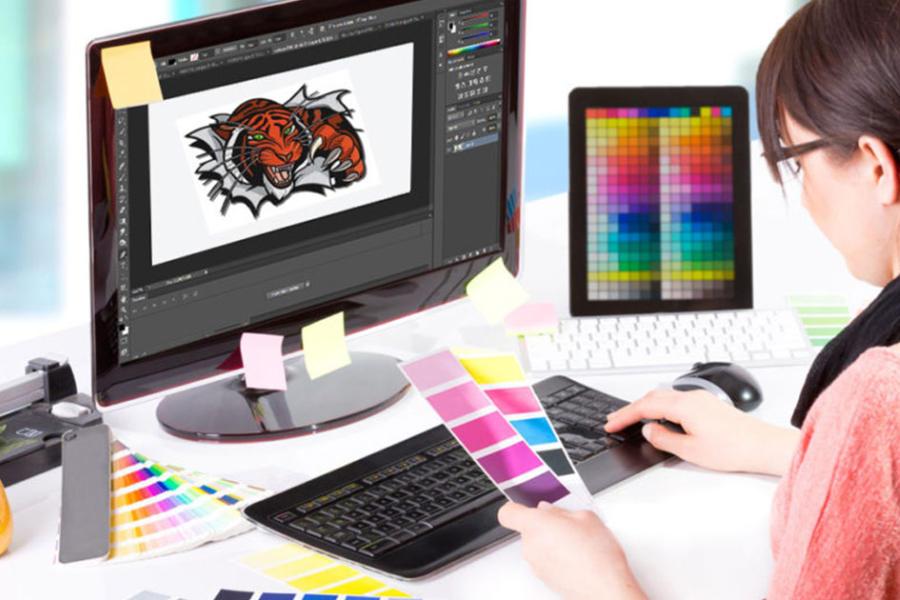 Graphic designer creating artwork in Adobe Photoshop with a tiger logo design to prepare for embroidery digitizing