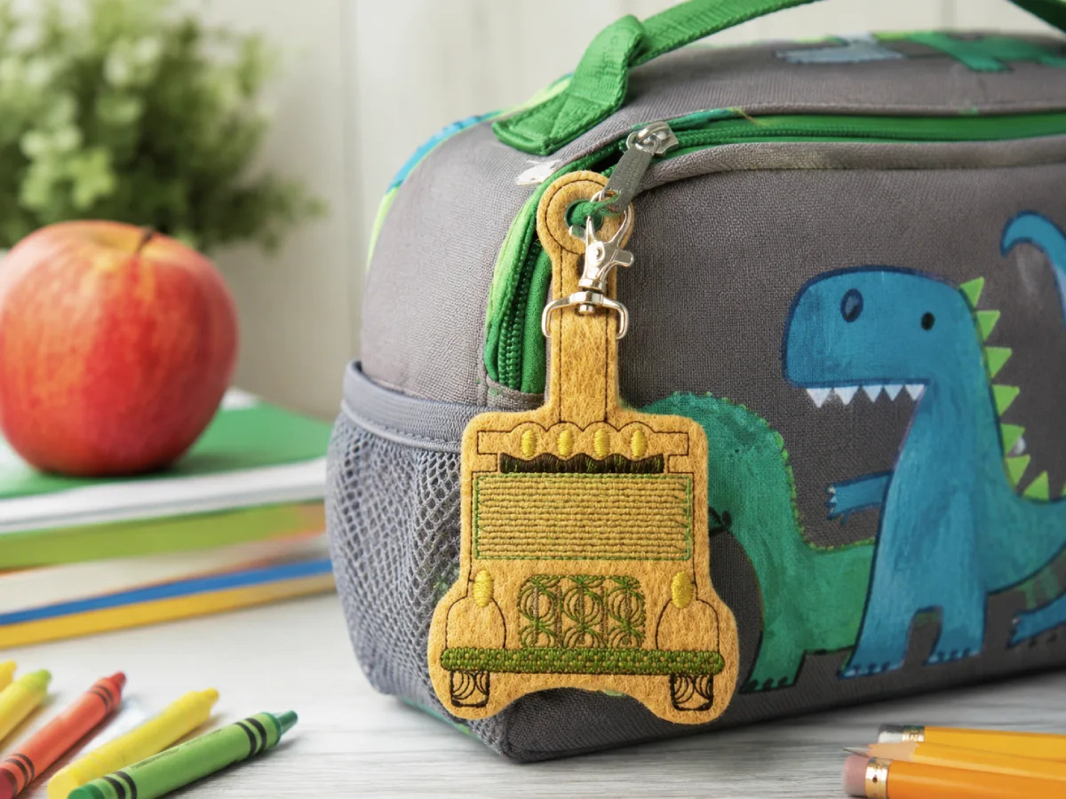 School bus feltie keychain clipped to a lunch bag — a fun, easy add-on for backpacks, classroom gifts, and back-to-school bundles.